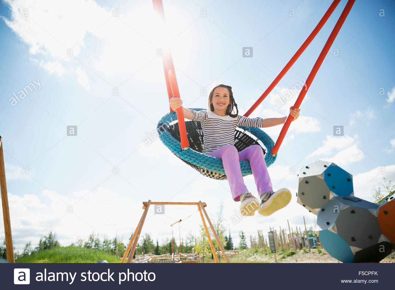 Ragazza spensierata swinging a sunny parco giochi Foto Stock