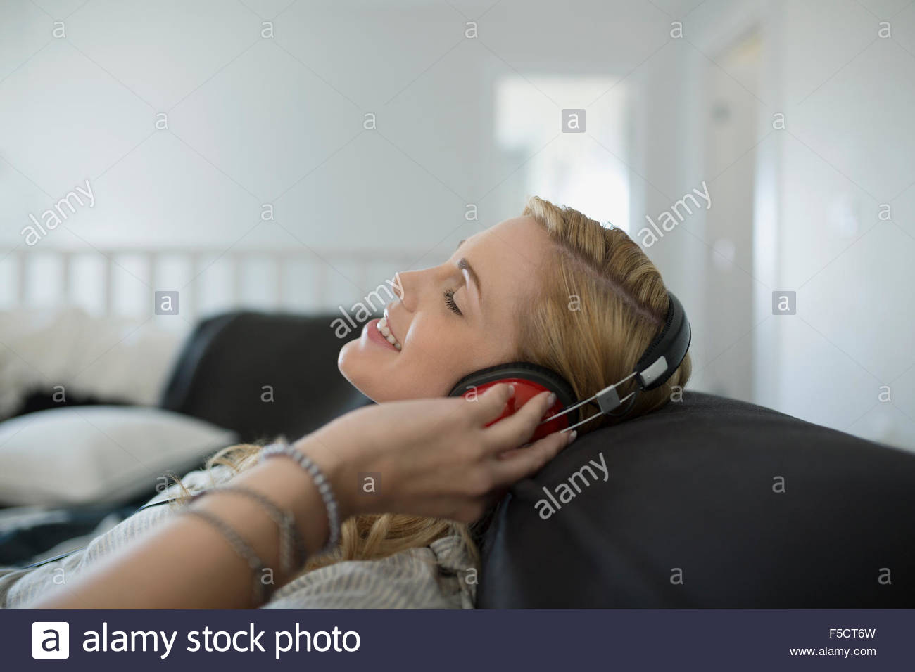 Donna con cuffie rilassarsi ascoltando musica divano Foto Stock