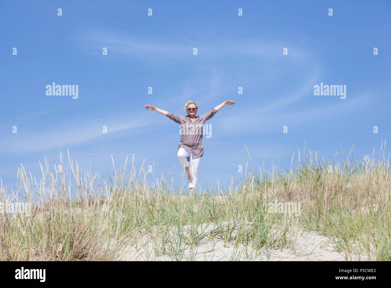 Un Senior donna fa sport sulla spiaggia di dune Foto Stock