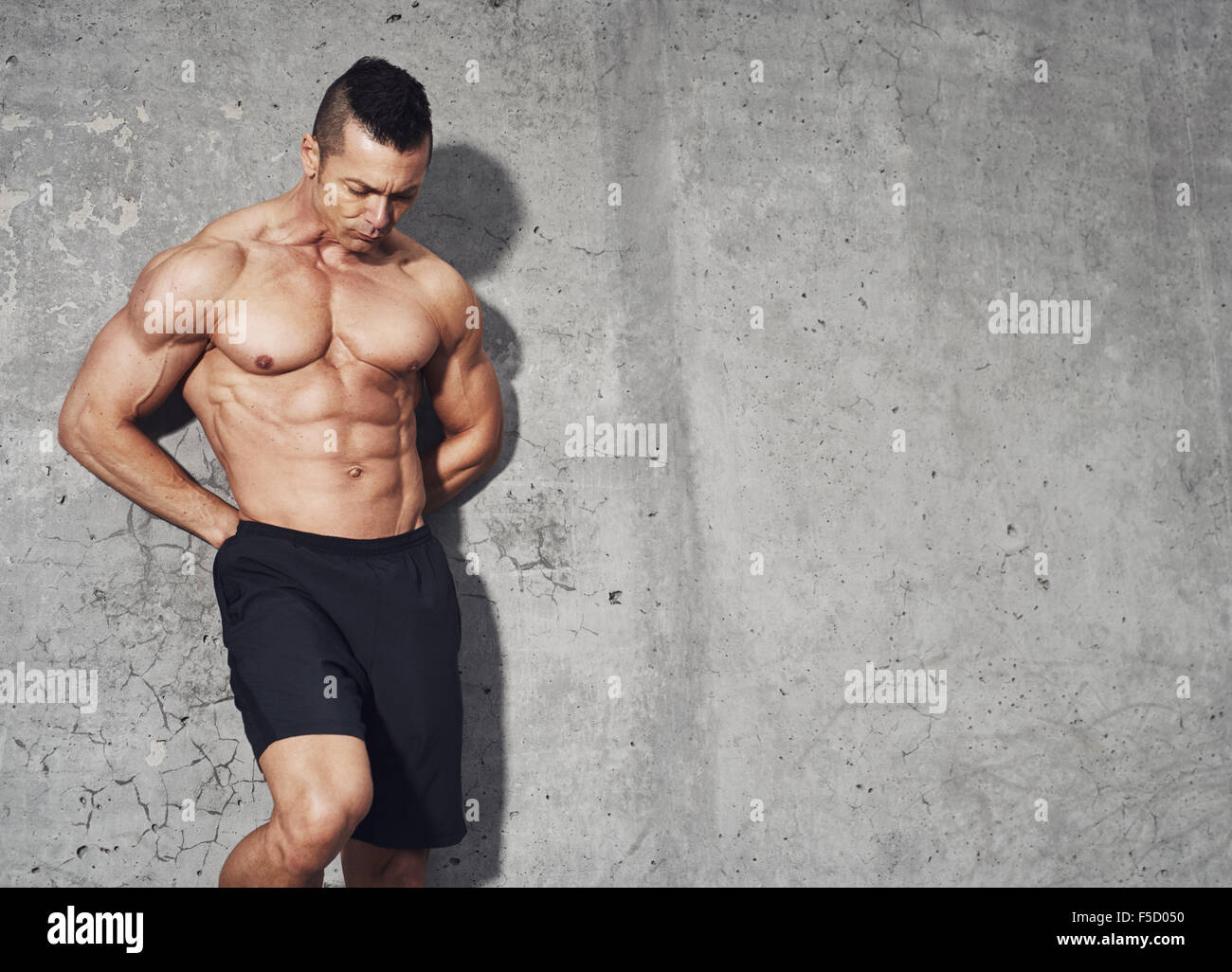 Maschio modello di fitness con muscoli addominali in piedi su uno sfondo grigio con una stanza per una copia in formato testo spazio. Foto Stock