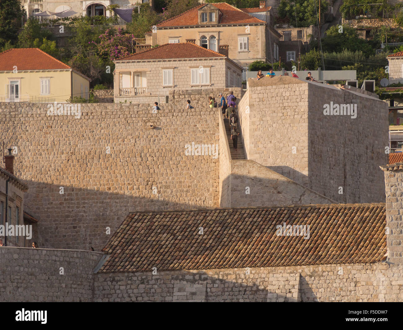 Dettaglio delle mura di fortificazione intorno alla città vecchia, Stari Grad, di Dubrovnik Croazia, turisti sightseeing, bassa luce del sole dorato Foto Stock