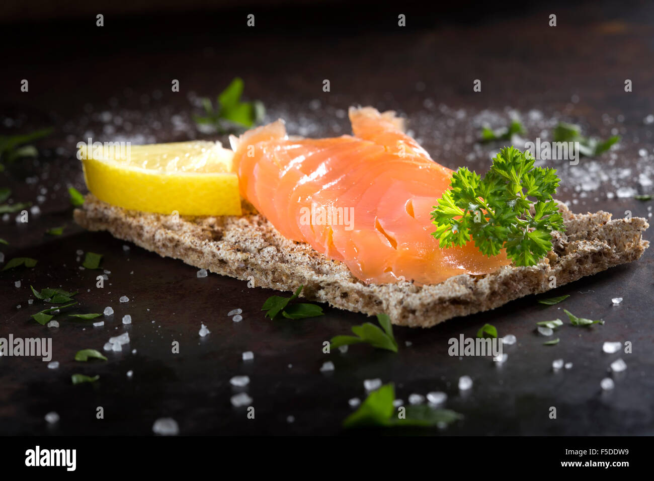 Salmone affumicato su cracker integrale con il prezzemolo, limone e sale Foto Stock