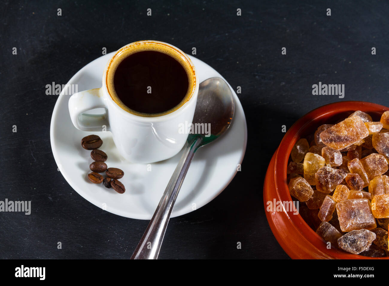 Tedesco roccia zucchero, brauner Kandis in terracotta ciotola marrone con tazza di caffè espresso. Foto Stock