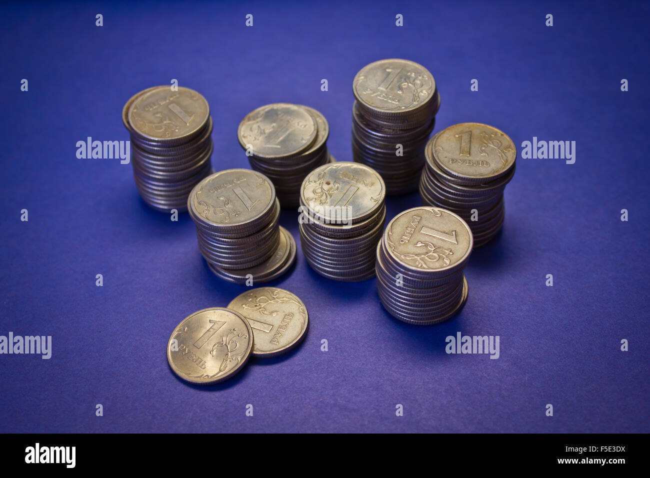 Un sacco di pile di monete su sfondo blu Foto Stock