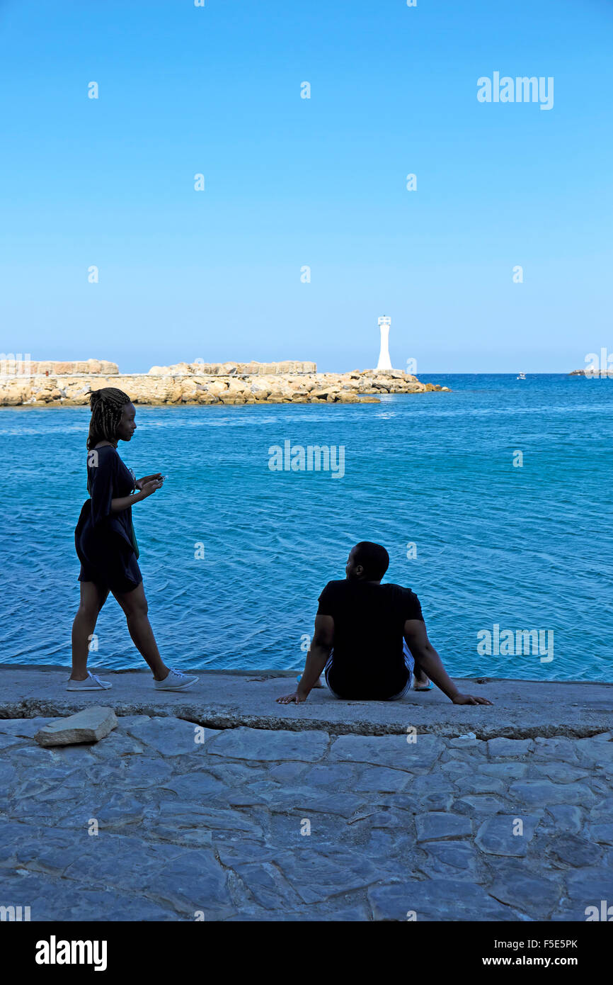 Persone sedute lungo la banchina all'entrata di Kyrenia porto di Cipro Nord KATHY DEWITT Foto Stock