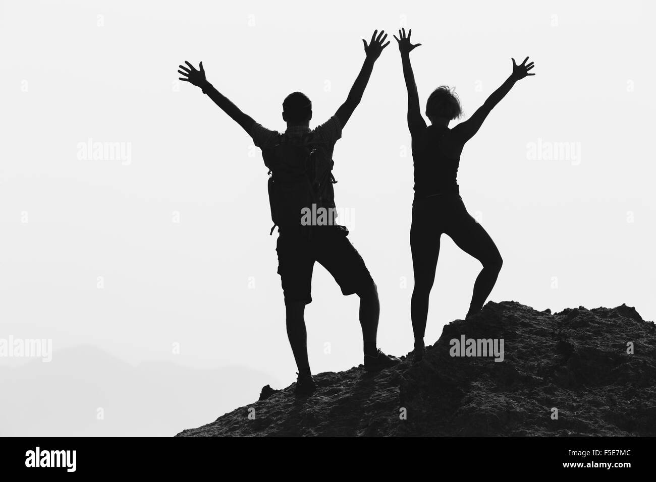 Coppia di successo conseguimento arrampicata o escursionismo, concetto aziendale con l uomo e la donna che celebra con le braccia in alto outstretch sollevata Foto Stock