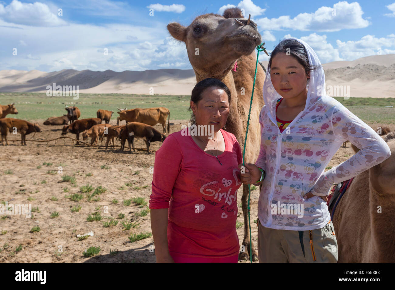 Nomadi allevatori di cammelli, con due hump Bactrian cammello con Khongoryn Els dune di sabbia dietro, deserto dei Gobi e Mongolia Foto Stock