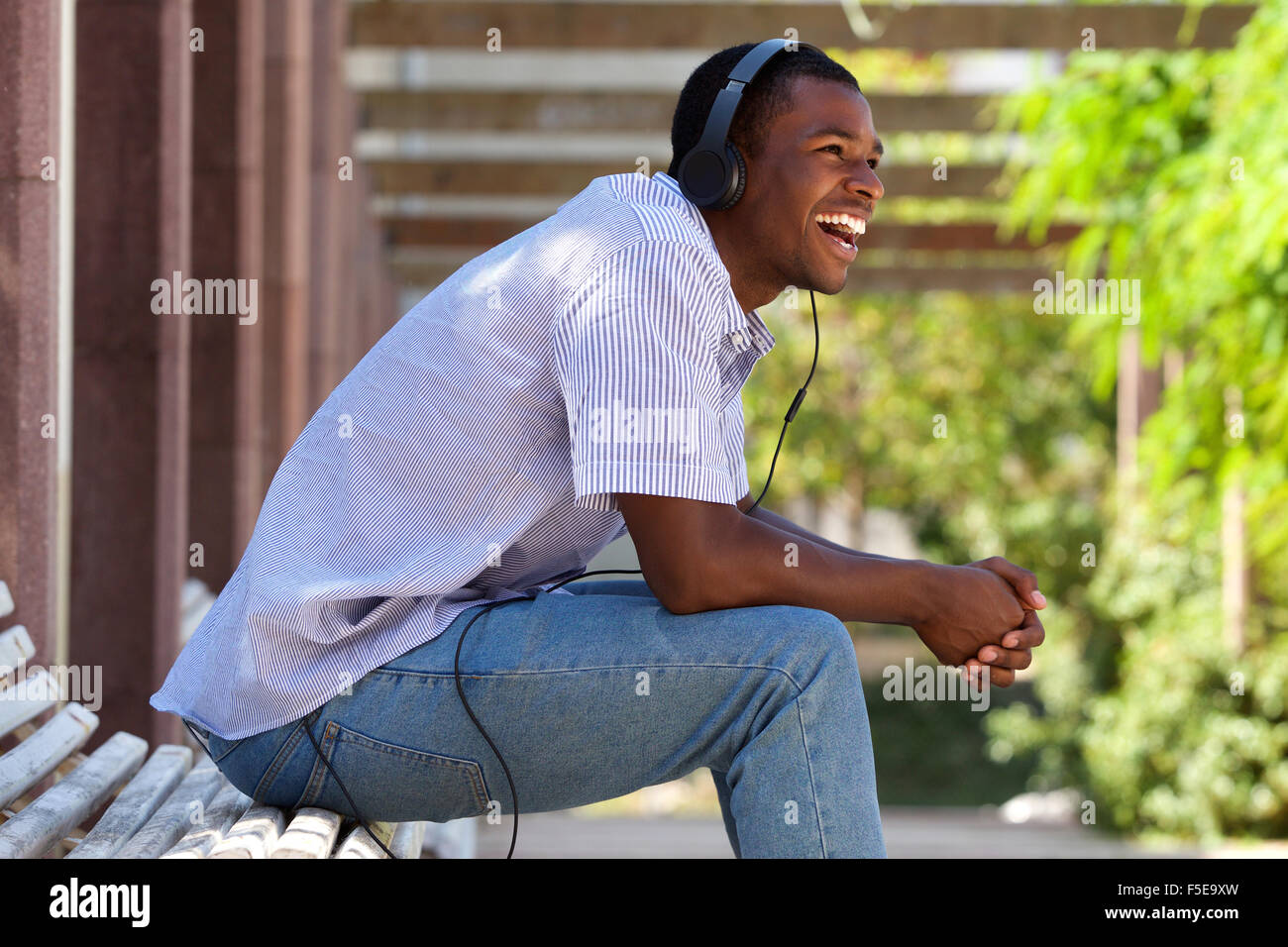 Lato ritratto di un ragazzo fantastico di ridere con le cuffie in posizione di parcheggio Foto Stock