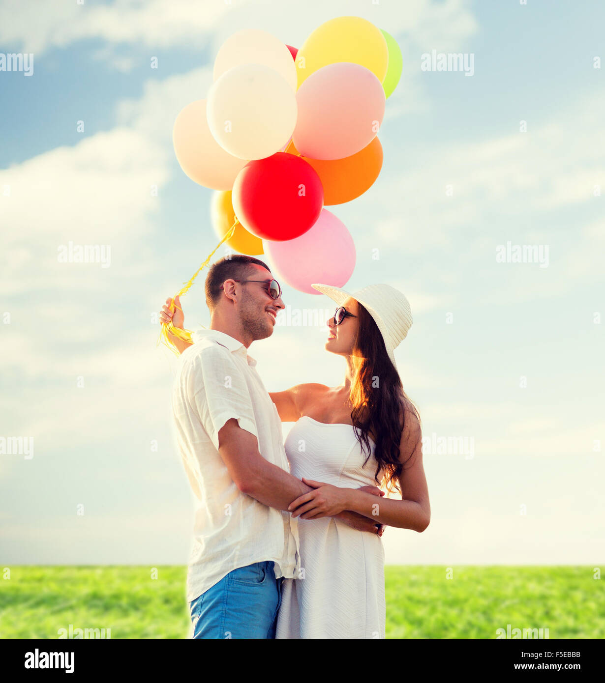 Coppia sorridente con aria palloncini all'aperto Foto Stock