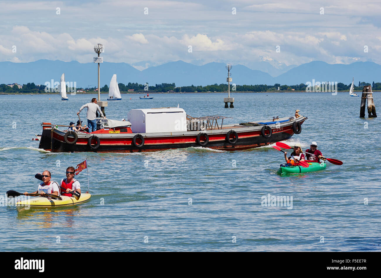 Barche a vela di una chiatta e kayak nella laguna veneta con sullo sfondo le Alpi Venezia Veneto Italia Europa Foto Stock