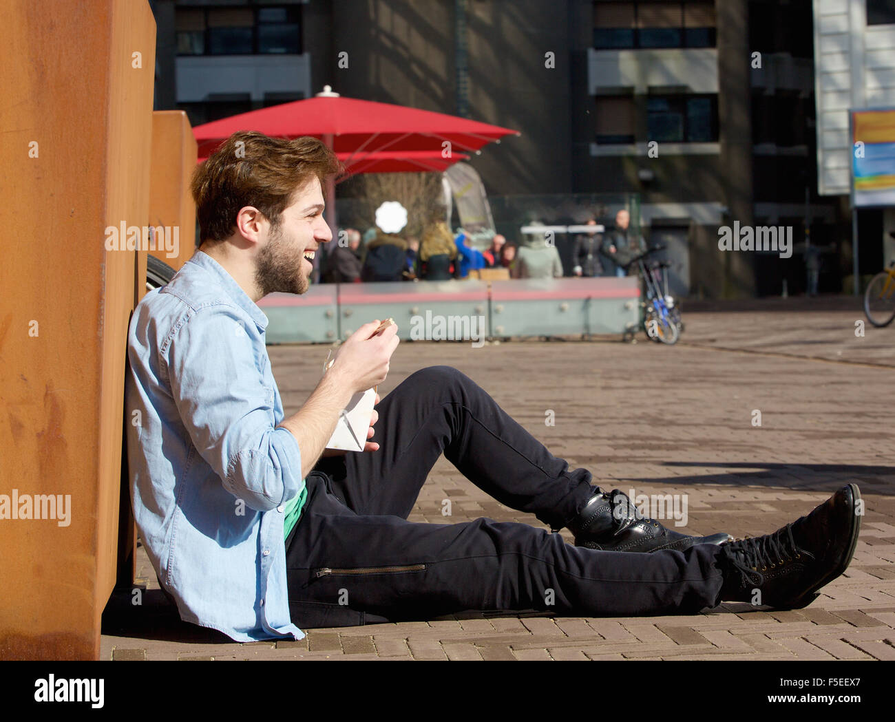 Ritratto di un uomo felice a mangiare cibo sulla pausa pranzo all'aperto Foto Stock
