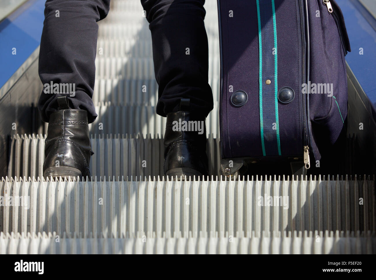 Ritratto da dietro di un uomo in piedi su escalator con borsa da viaggio Foto Stock