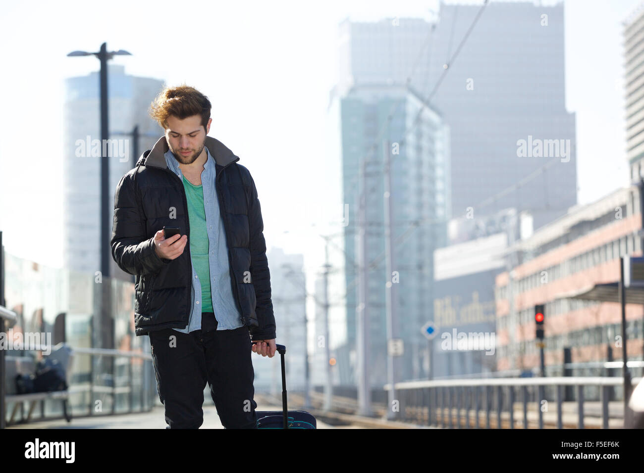 Ritratto di un bel giovane uomo a camminare con il sacchetto e il telefono cellulare nella città Foto Stock