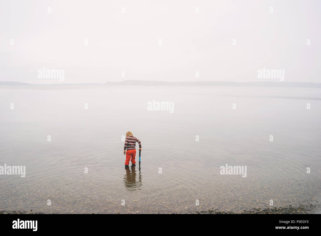 Ragazzo in piedi in acqua poco profonda in un lago Foto Stock