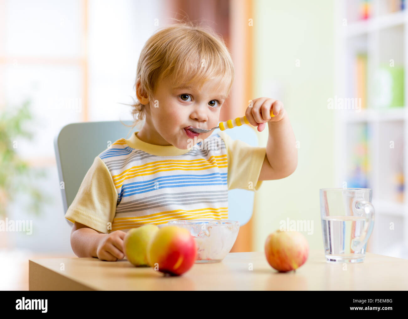 Bambino di mangiare cibo sano e con la mano sinistra a casa Foto Stock