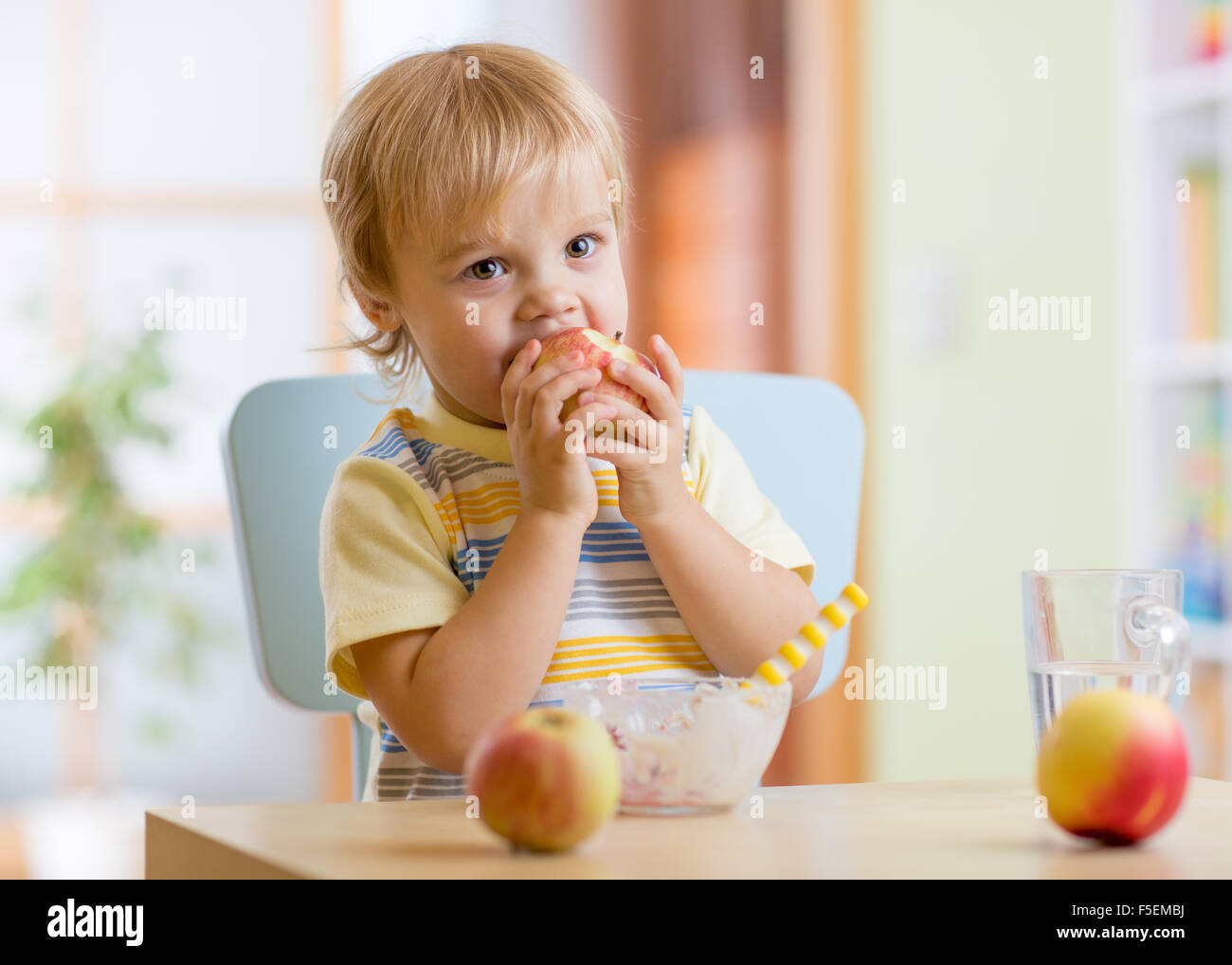 Bambino apple mangiare a cena in un asilo nido a casa Foto Stock