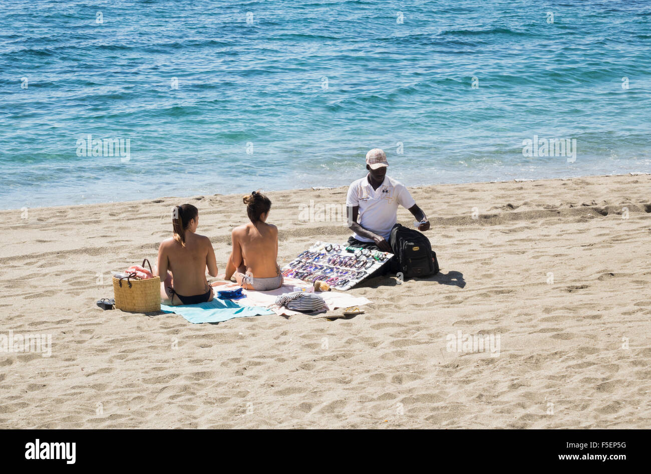 L'uomo africano vendita di occhiali da sole per i turisti sulla spiaggia di Marbella, Spagna Foto Stock
