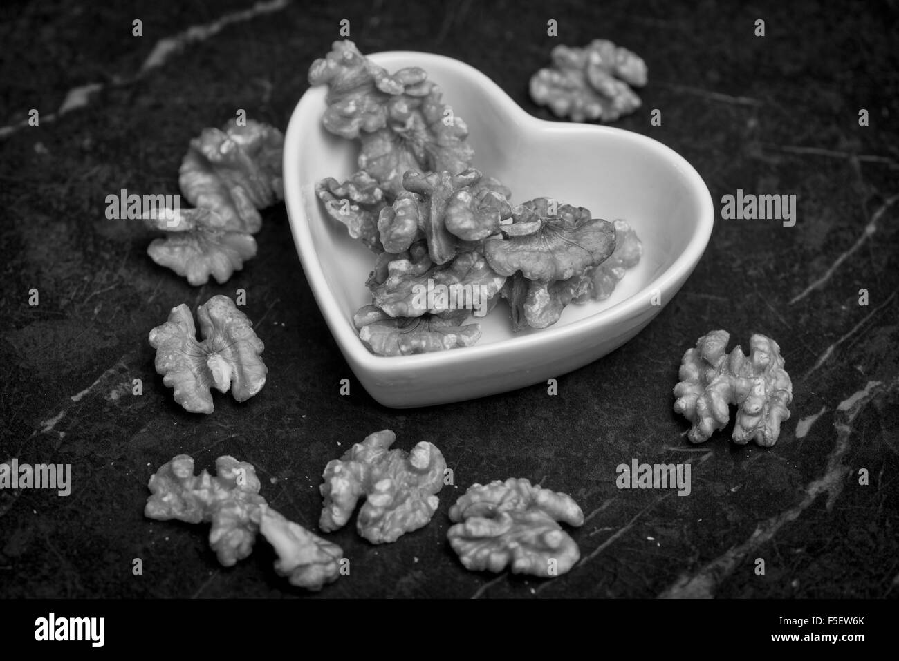 Le noci in un cuore ciotola sagomata, in bianco e nero. Foto Stock