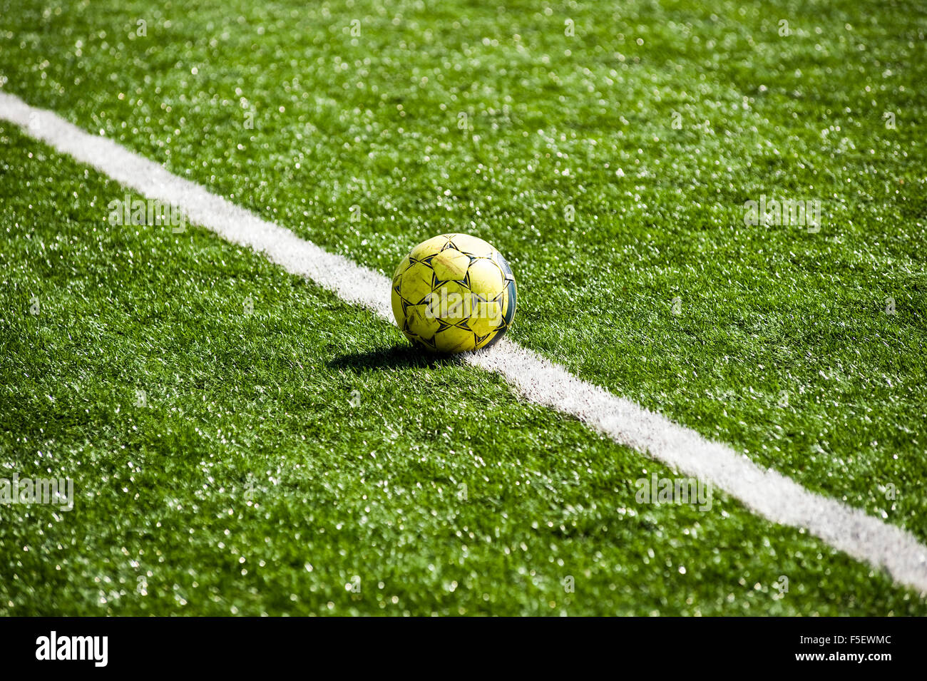 Usato, giallo pallone da calcio giace sulla linea bianca. Foto Stock