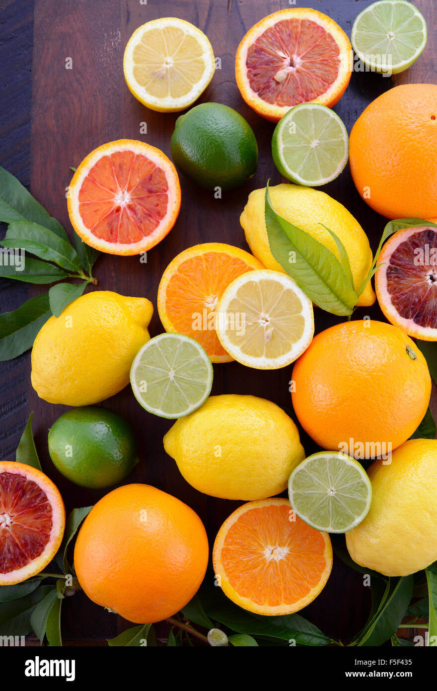 Mescolati gli agrumi tra cui ombelico e sangue arance, limoni e limette sul legno scuro tavolo. Foto Stock