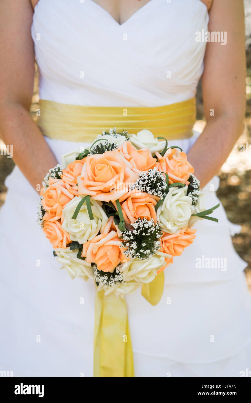 Una sposa tenendo un bouquet di fronte la sua vita Foto Stock