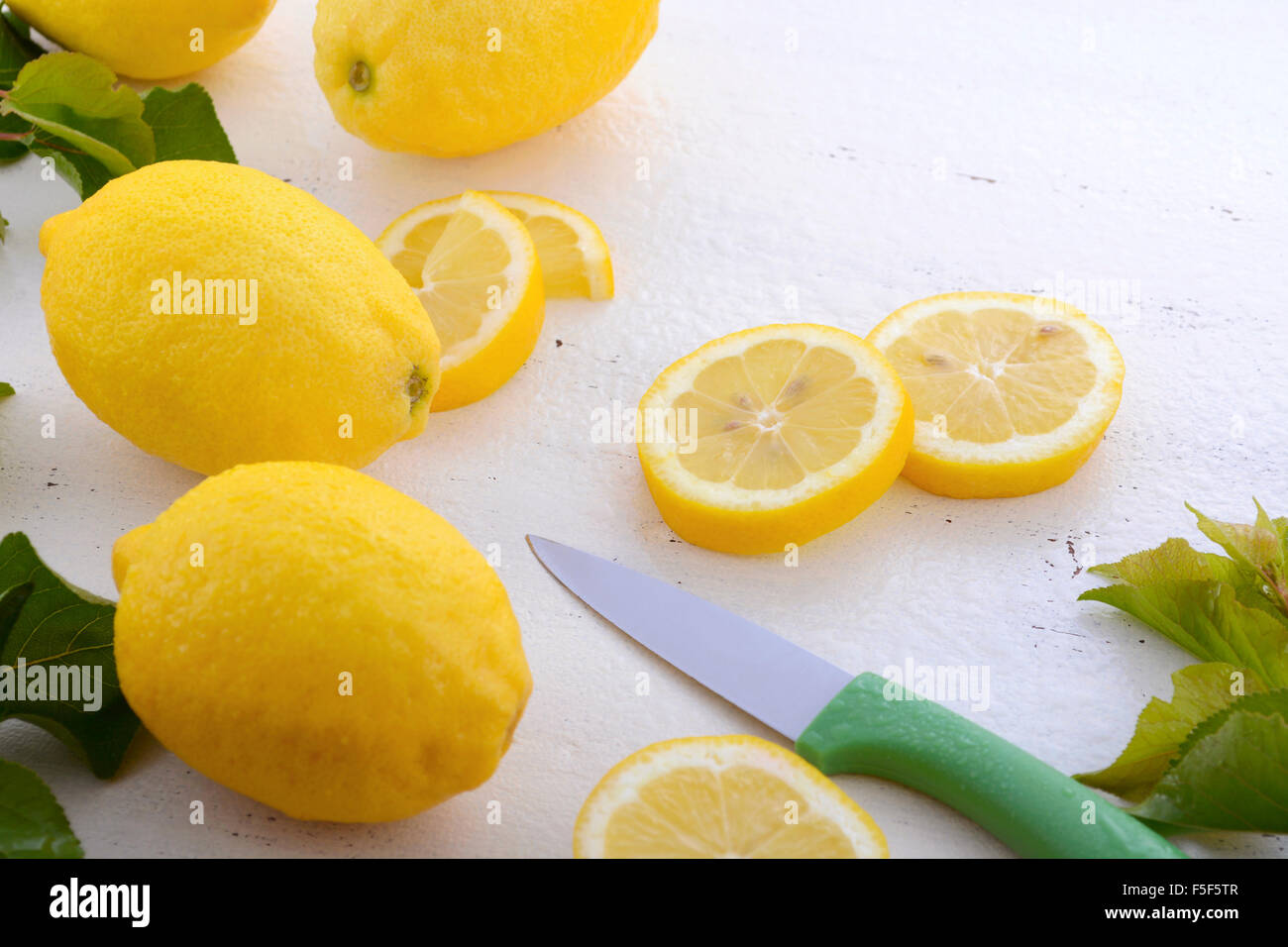 Disco per affettare e preparare i limoni sul bianco rustico tavolo in legno. Foto Stock