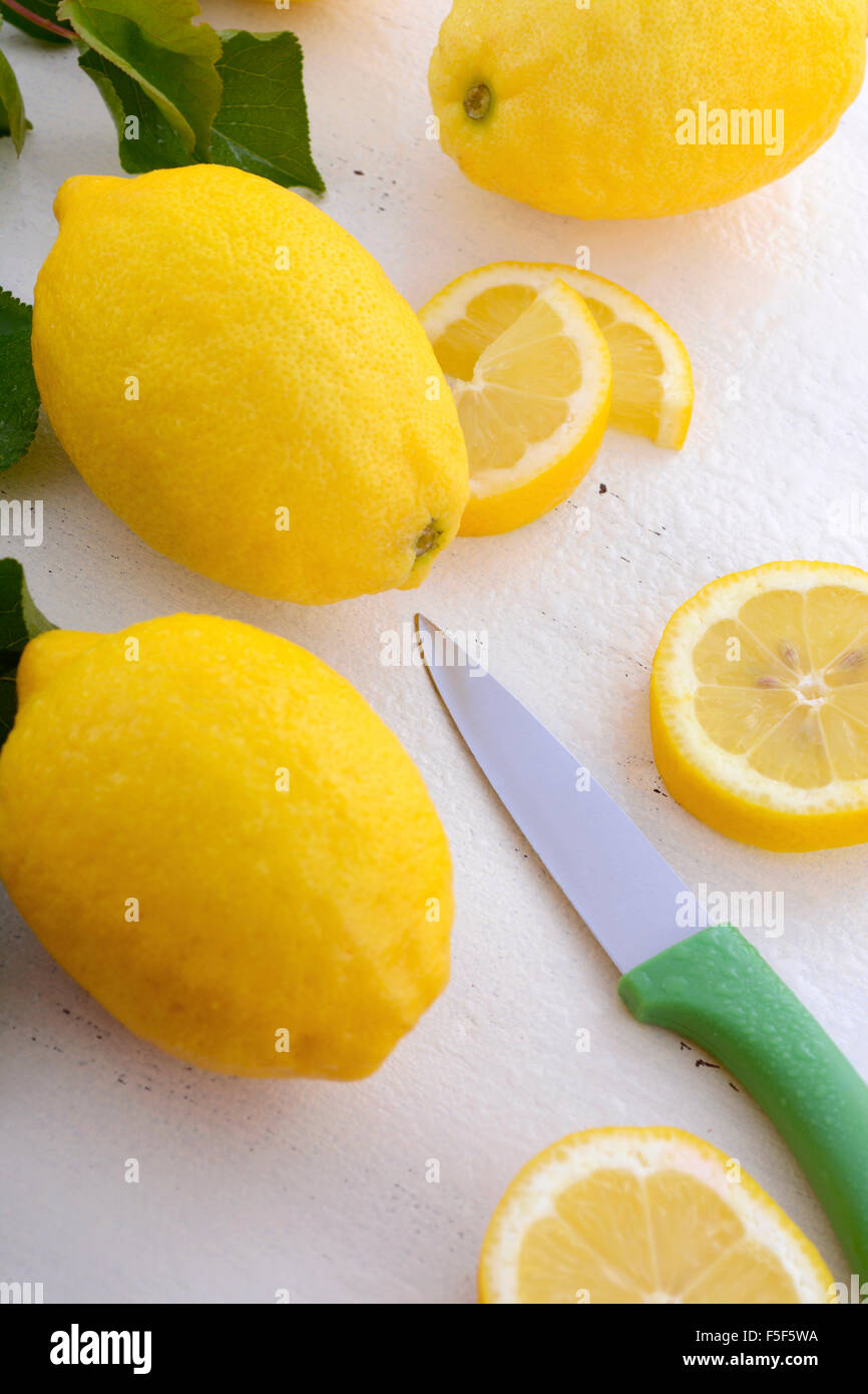 Disco per affettare e preparare i limoni sul bianco rustico tavolo in legno. Foto Stock