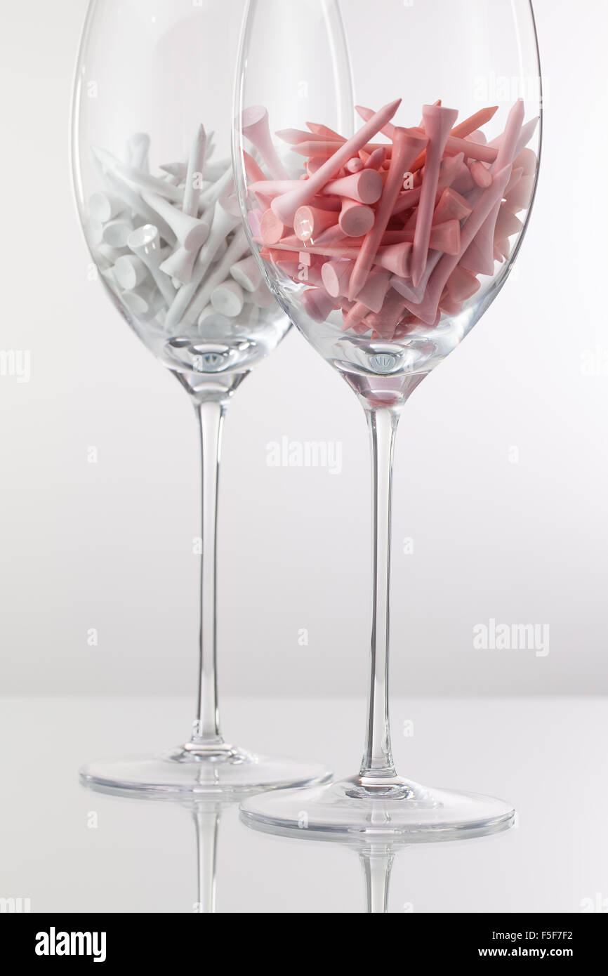Due bicchieri di vino e attrezzature da golf su sfondo bianco Foto Stock