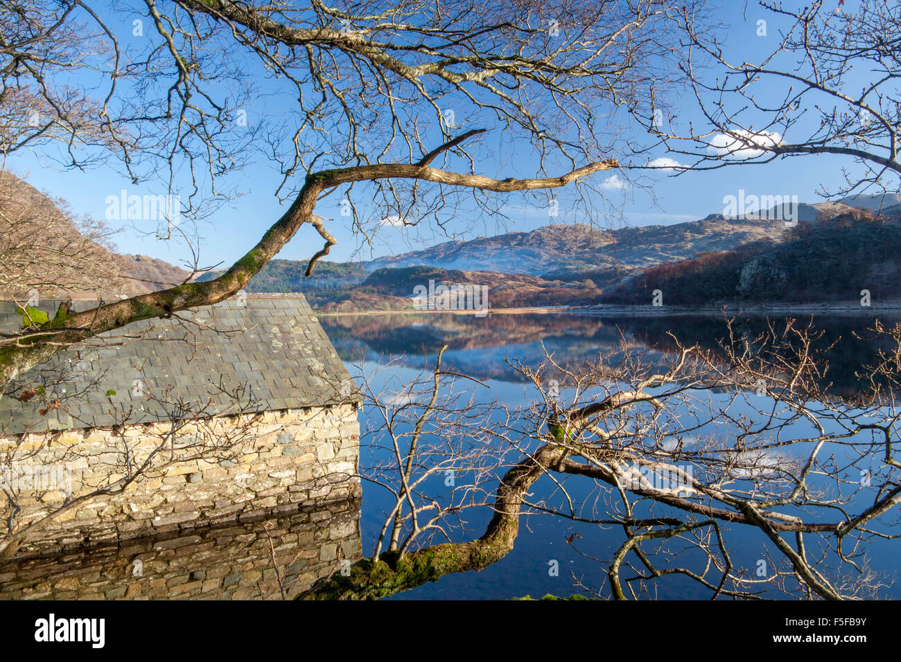 Llyn Dinas lago con pietra boathouse riflessa in acqua ancora il Parco Nazionale Snowdonia Gwynedd North Wales UK Foto Stock