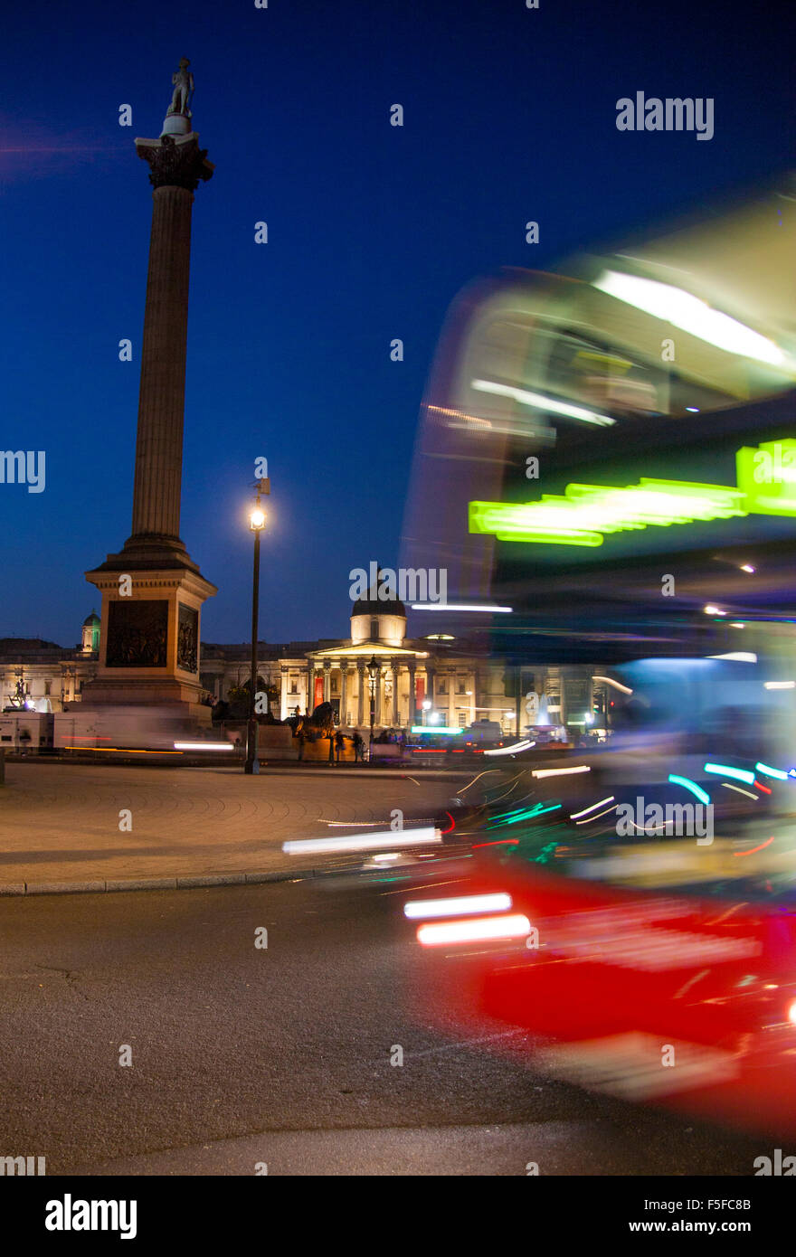 Trafalgar Square di Nelson's Colonna e Galleria Nazionale di notte con red bus londinese passando attraverso con motion blur Foto Stock
