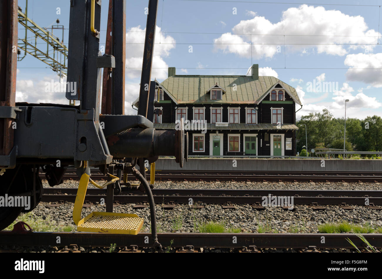 Carro ferroviario i bumper in primo piano e una vecchia stazione ferroviaria del nord della Svezia in background. Foto Stock