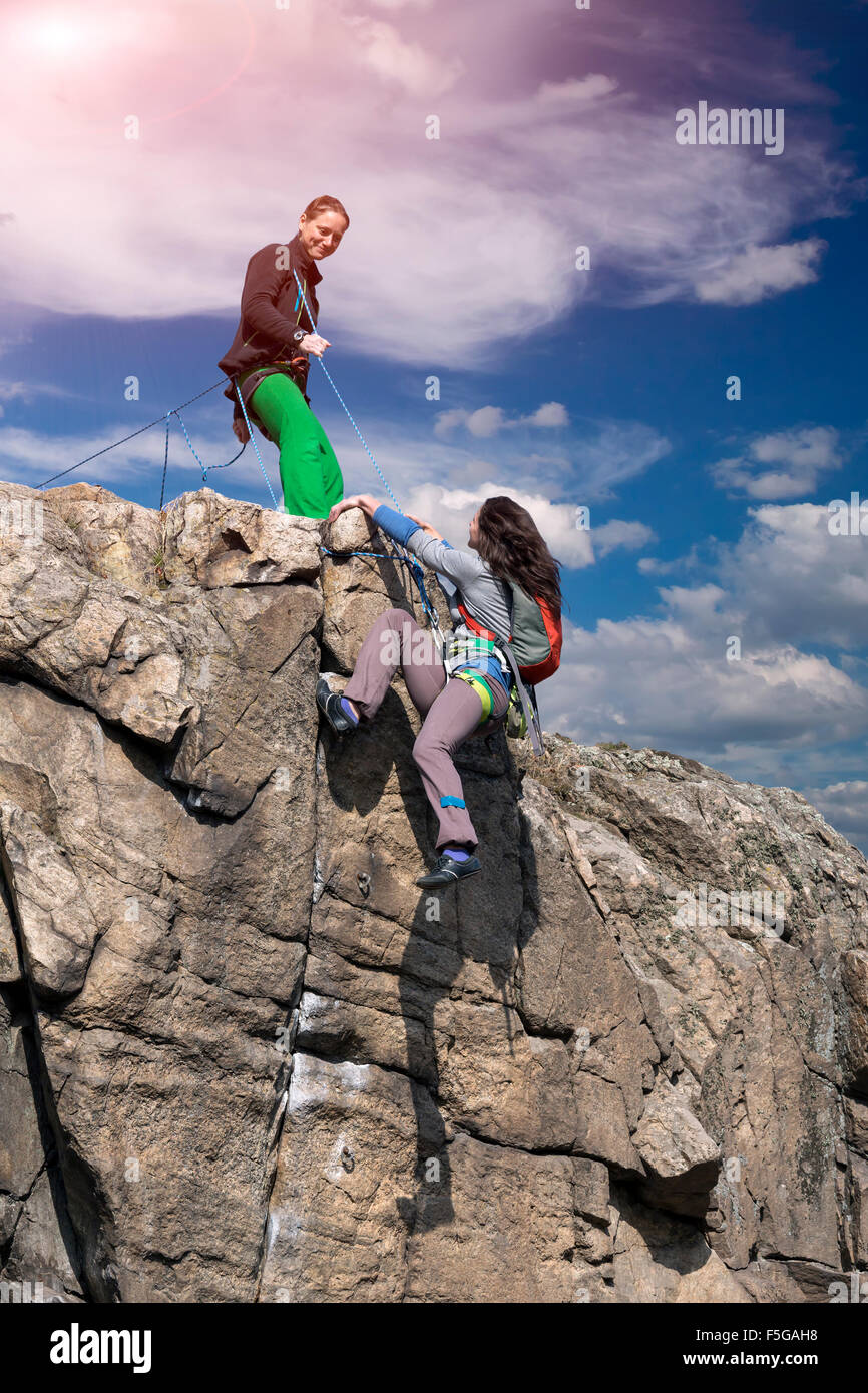 . Gli arrampicatori femmina si aiuta a vicenda sulla parete di roccia Foto Stock