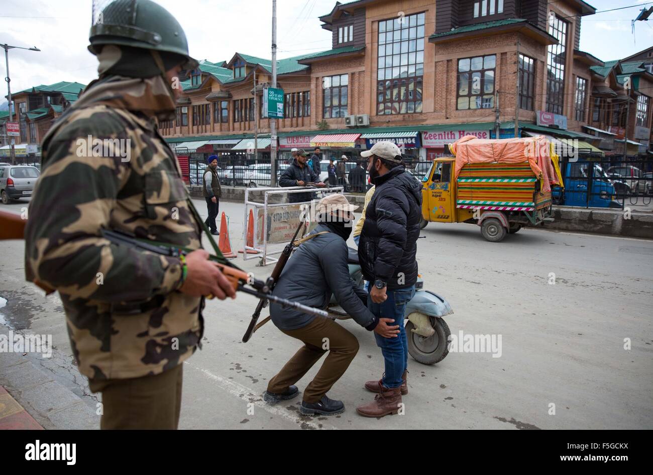 Srinagar, Indiano-controllato del Kashmir. 4 Novembre, 2015. Un poliziotto indiano frisks un pedone come un Indiano soldato paramilitari (L) Sta di guardia ad un checkpoint temporanea a Srinagar, capitale estiva di Indiano-Kashmir controllata, nov. 4, 2015. Le autorità di Indiano-Kashmir controllata di sicurezza rinforzato davanti al Primo Ministro indiano Narendra Modi la visita programmata per sabato. © Javed Dar/Xinhua/Alamy Live News Foto Stock