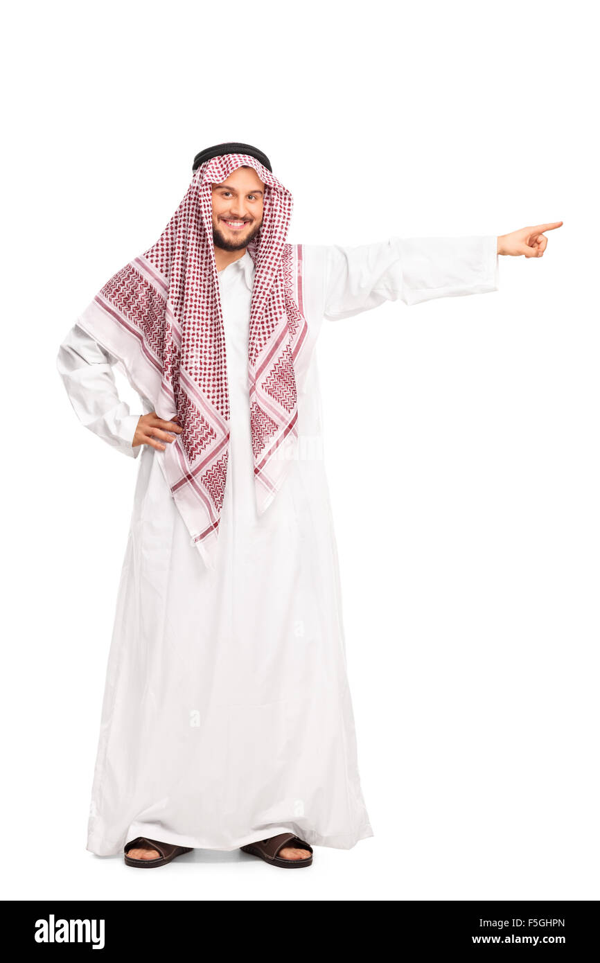 A piena lunghezza Ritratto di una giovane maschio in arabo una tunica bianca che punta verso destra con la sua mano isolati su sfondo bianco Foto Stock