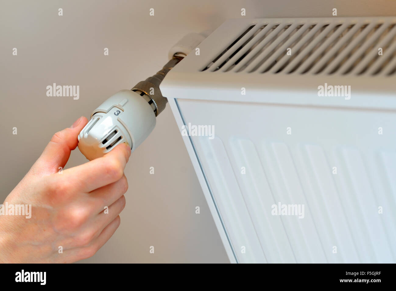 Donna di mano del termostato di regolazione nel periodo invernale Foto Stock