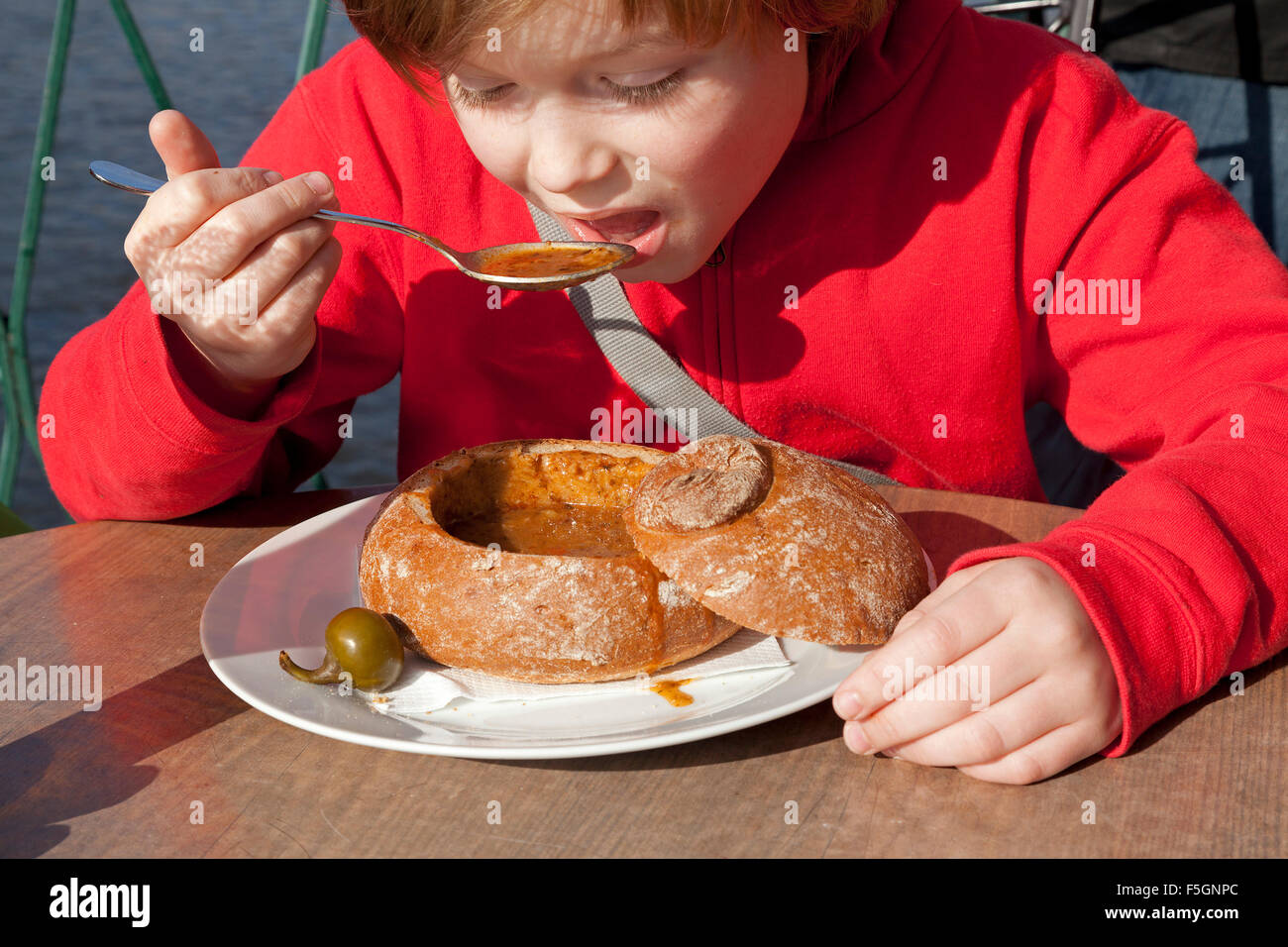 Ragazzo di mangiare zuppa di gulasch in pane, Praga, Repubblica Ceca Foto Stock