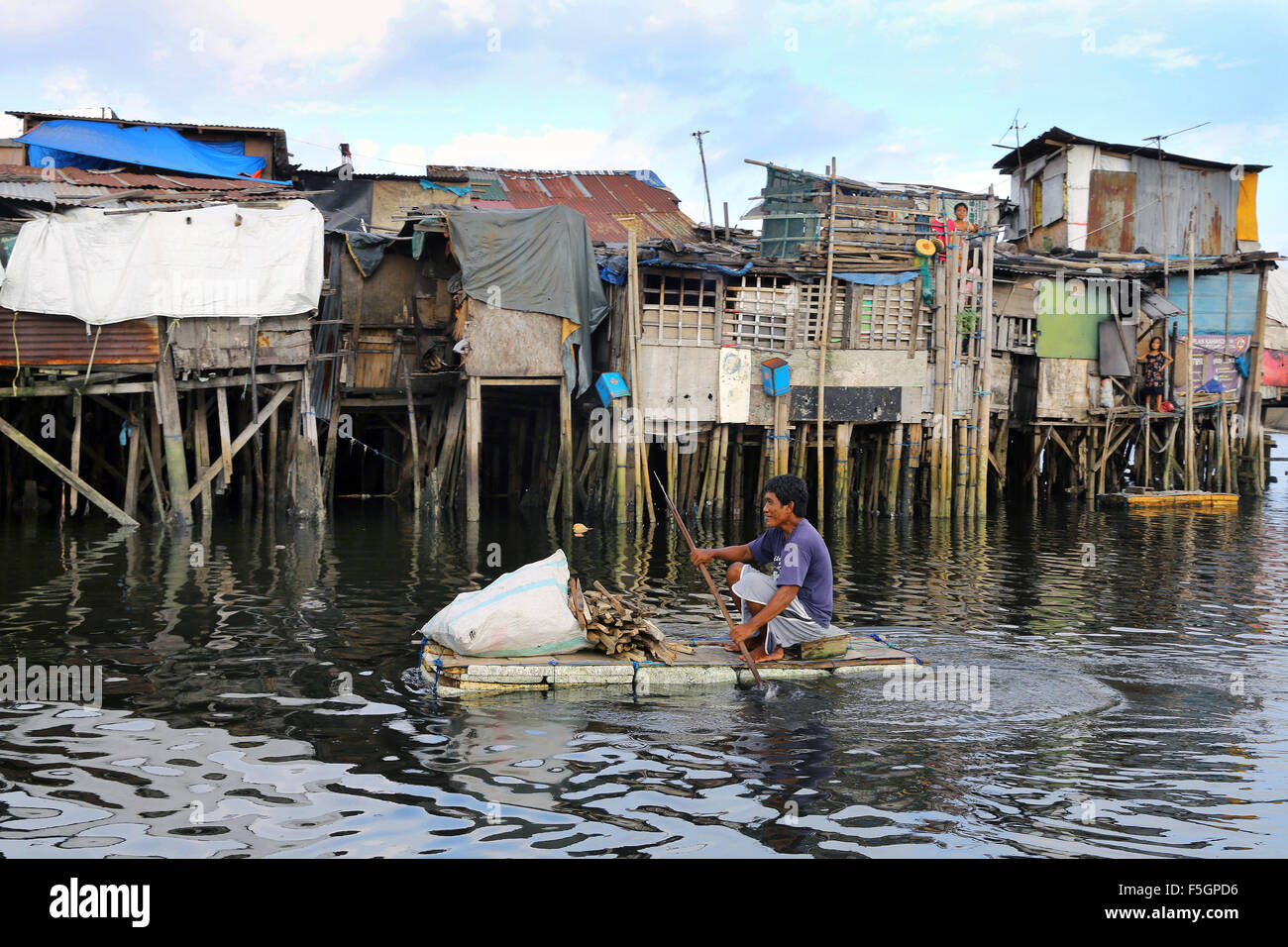 Manila nelle Filippine: residente di un quartiere povero che vivono in capanne su palafitte con legna da ardere su un galleggiante in polistirolo espanso, Tondo township, Manila, Filippine Foto Stock