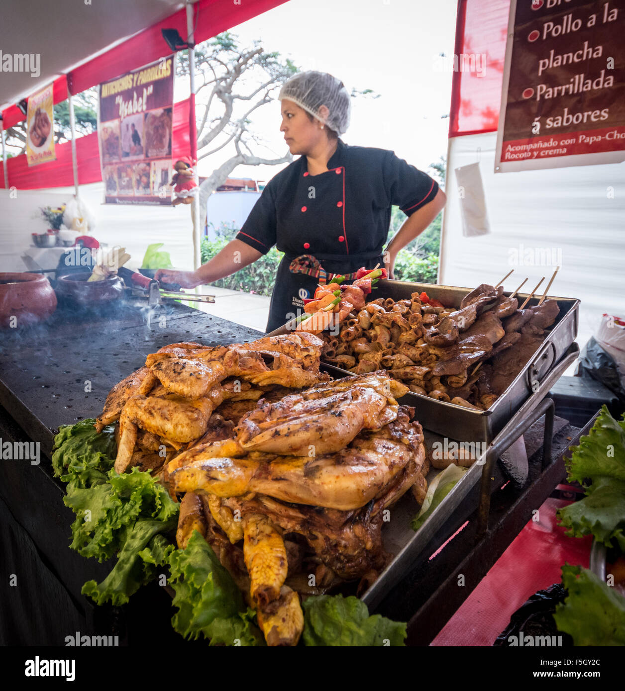 Venditore ambulante vende pollo grigliato e anticuchos (cuore bovino su spiedino) ad una fiera alimentare nel Barranco del distretto di Lima Peru Foto Stock