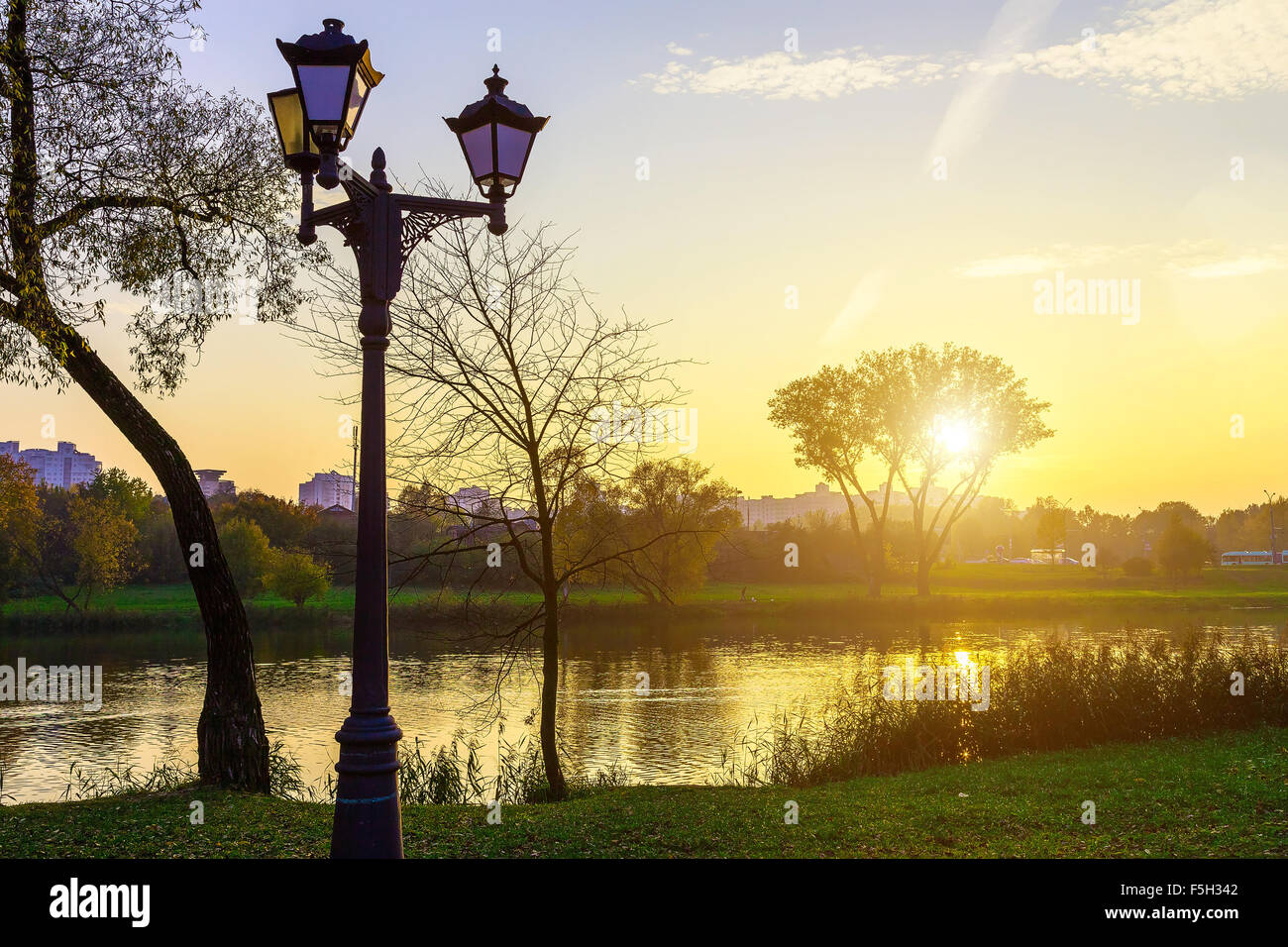 Il paesaggio del parco cittadino con lanterne dal lago al tramonto in autunno Foto Stock