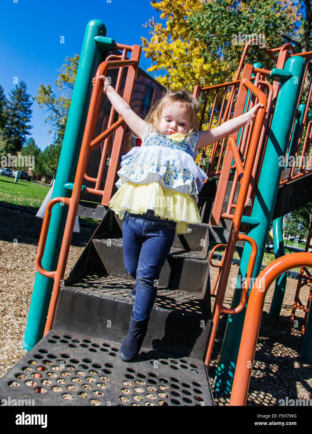 Quattro anni di bambina a giocare al di fuori su una giungla palestra in un parco Foto Stock