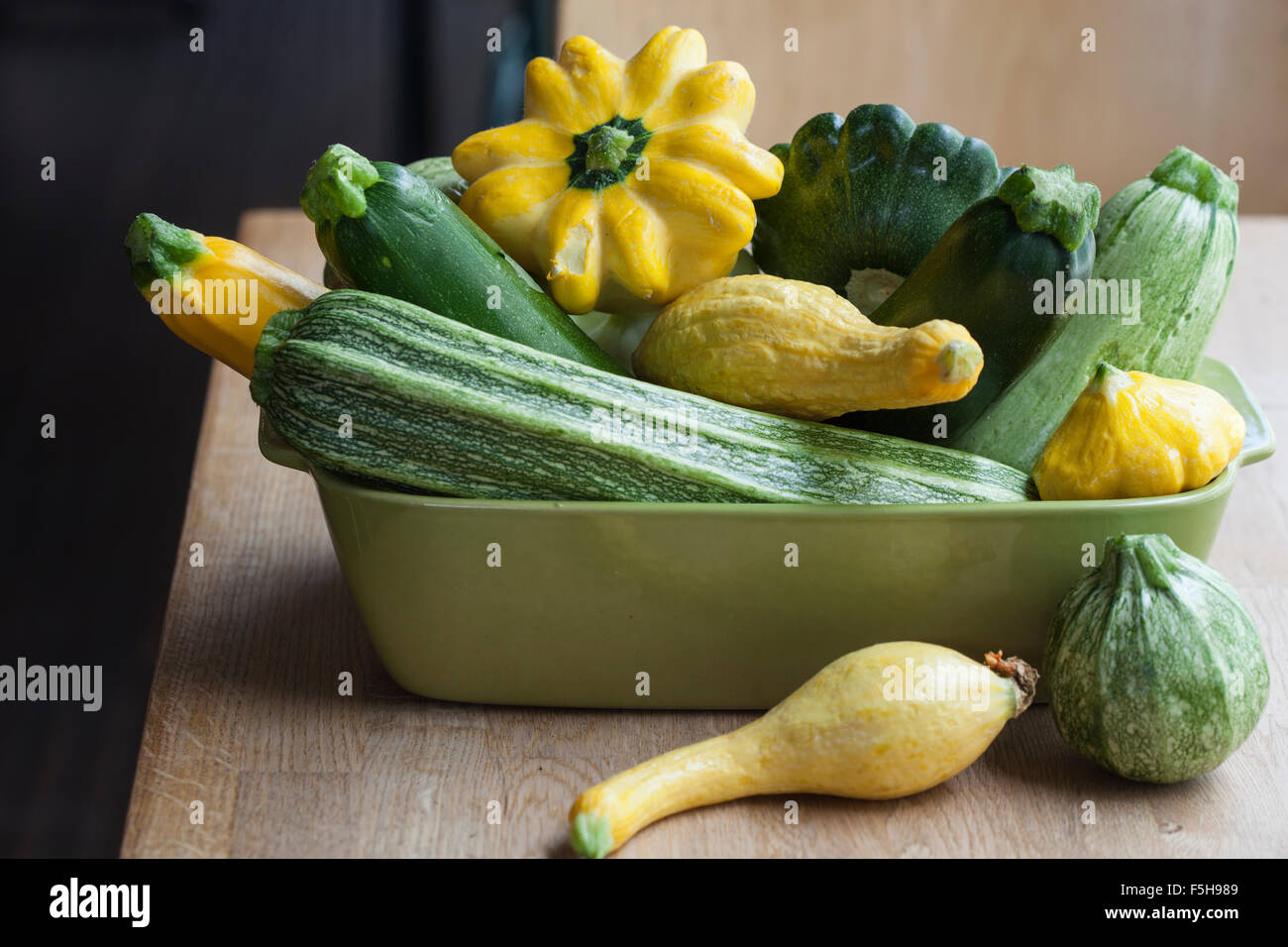 Una varietà di estate squash in un verde rettangolare piatto, su un tavolo Foto Stock
