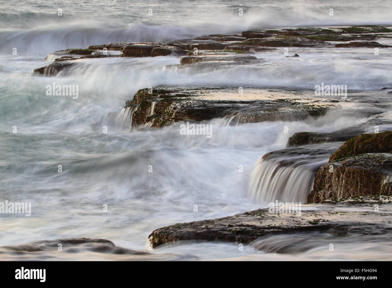 Aumento di onde e crash tra le rocce a Scarbrough nel NSW, Australia. Foto Stock