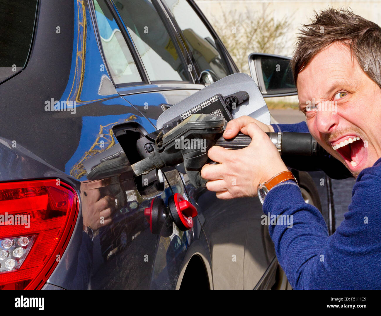 Molto arrabbiato uomo su una stazione di rifornimento di carburante Foto Stock