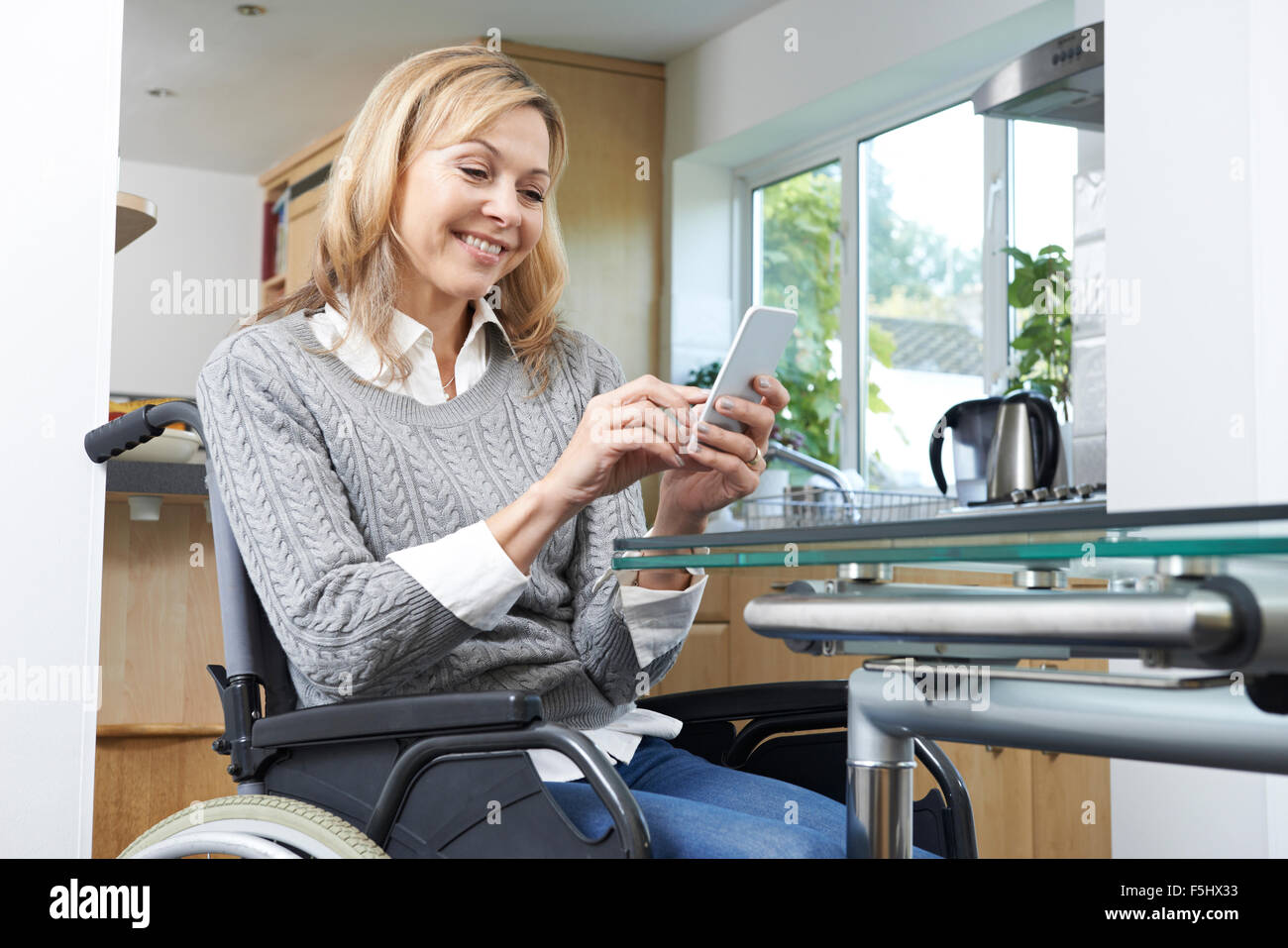 Donna disabile in carrozzella sms sul cellulare a casa Foto Stock