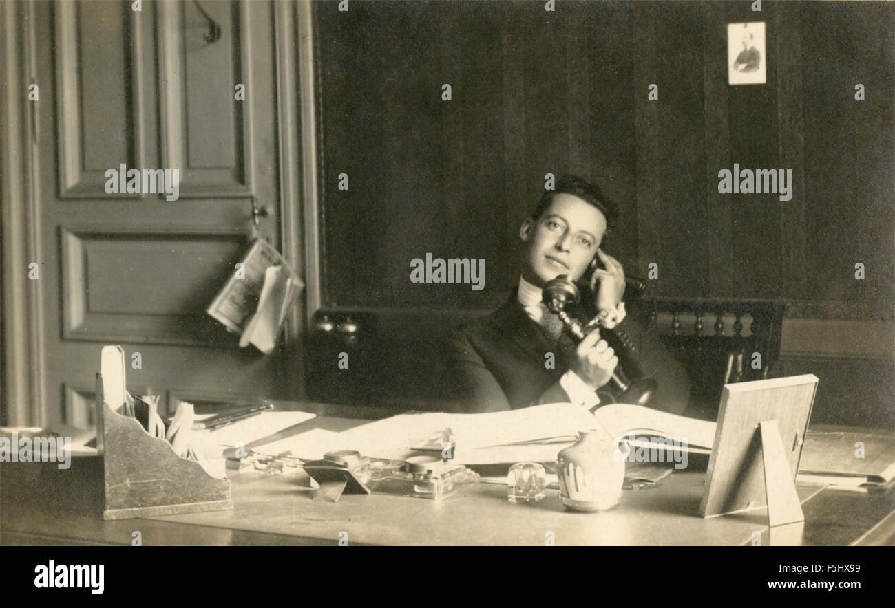 Un uomo al telefono dietro la sua scrivania, Italia Foto Stock