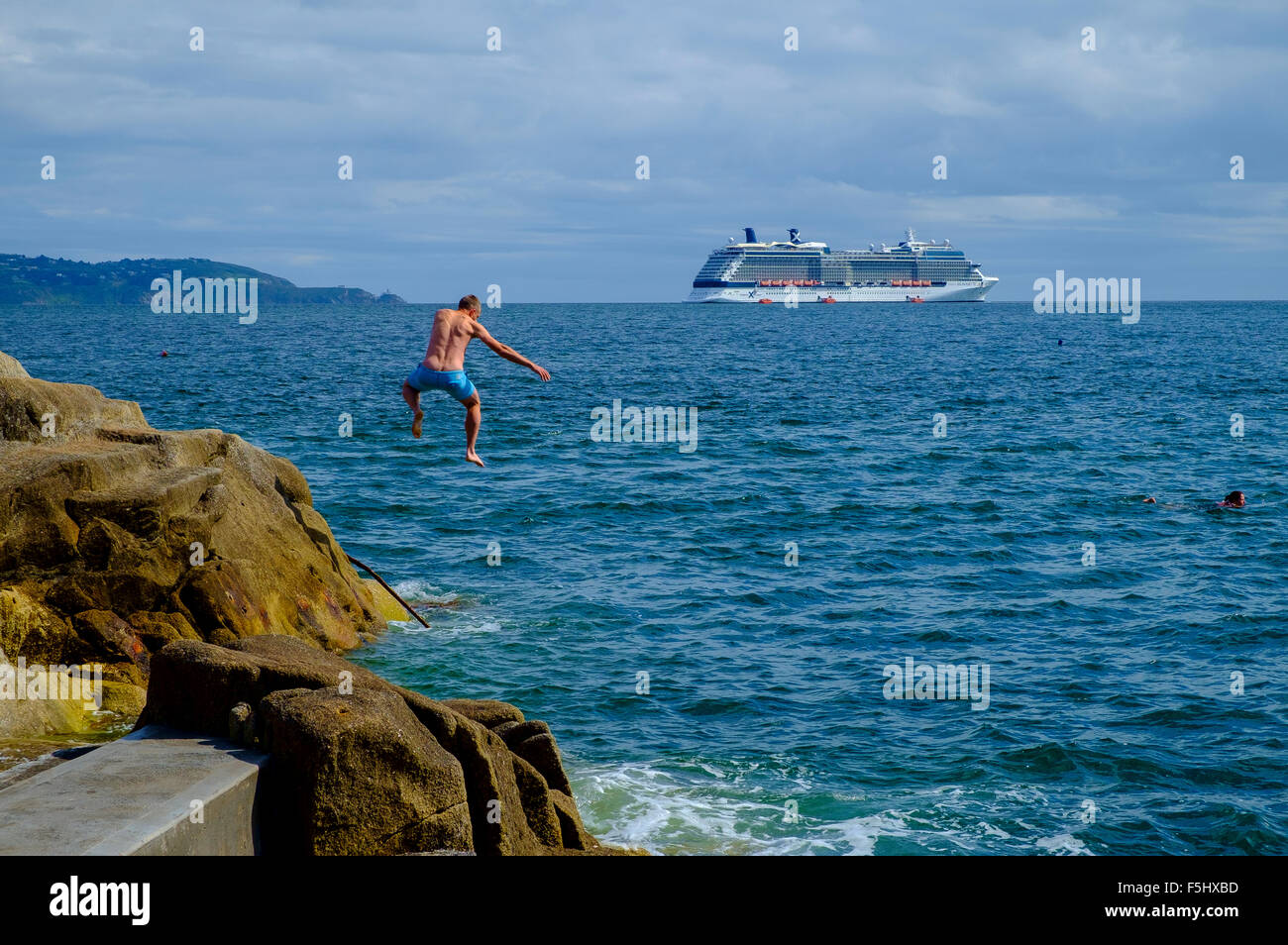 L'uomo diving jumping Rocks off in mare la nave di crociera Foto Stock