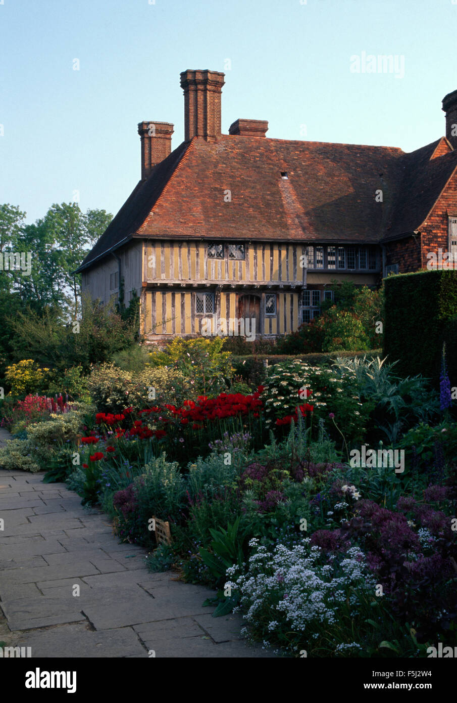 Colorata fioritura piante perenni ed annuali in una vasta frontiera nel giardino di una grande Tudor House Foto Stock