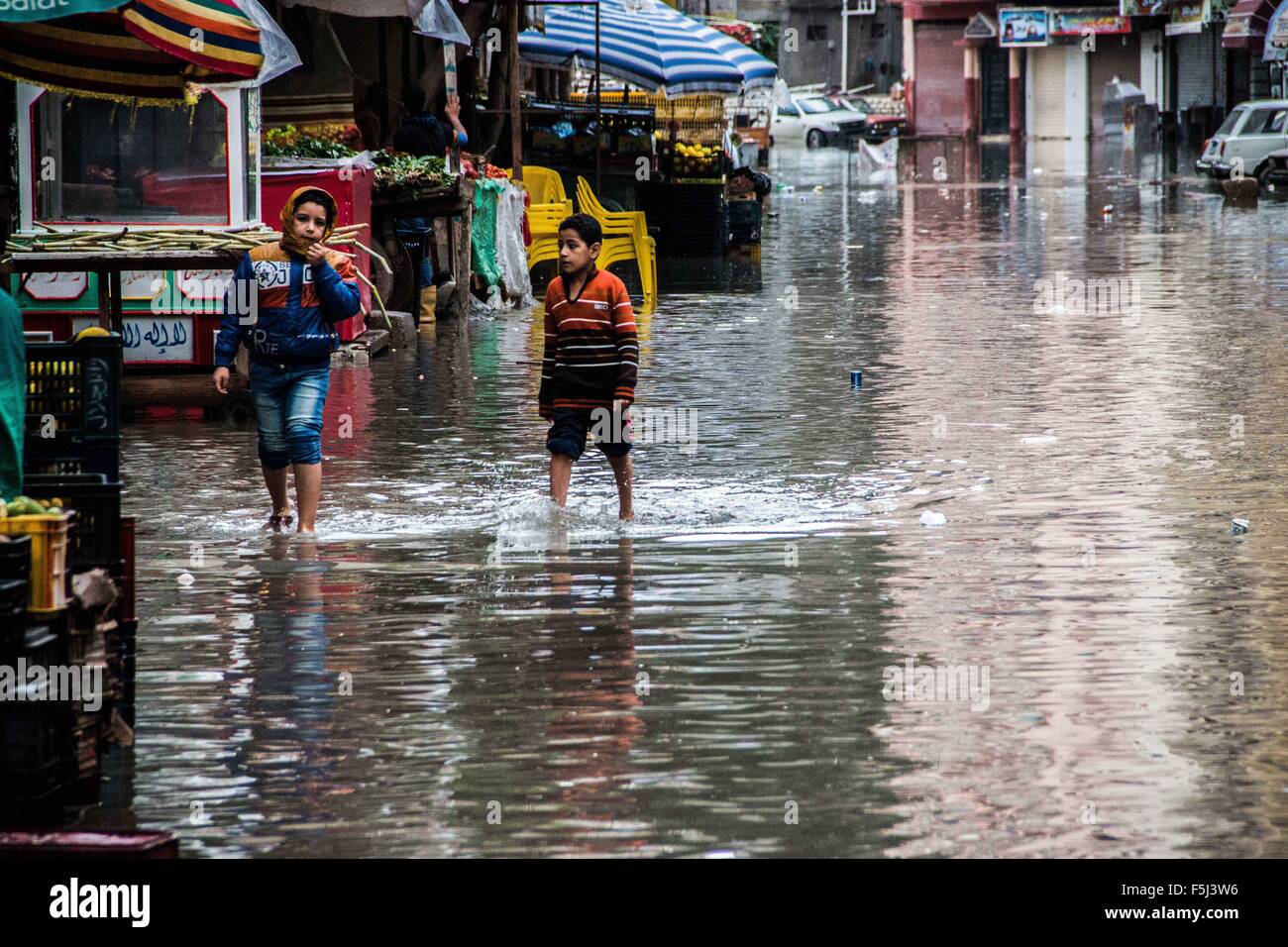 Alessandria ad Alessandria, Egitto. 5 Novembre, 2015. Ragazzi egiziani a piedi in una strada allagata a seguito heavy rain storm, in Alessandria, Egitto, 5 novembre 2015. Undici persone sono state uccise in alluvioni in Beheira provincia a nord del Cairo, una fonte di sicurezza detto e autorità hanno evacuato 100 persone provenienti da un paese in provincia come l'Egitto risente di un secondo round di maltempo in meno di un mese di credito: Amr Sayed/immagini APA/ZUMA filo/Alamy Live News Foto Stock