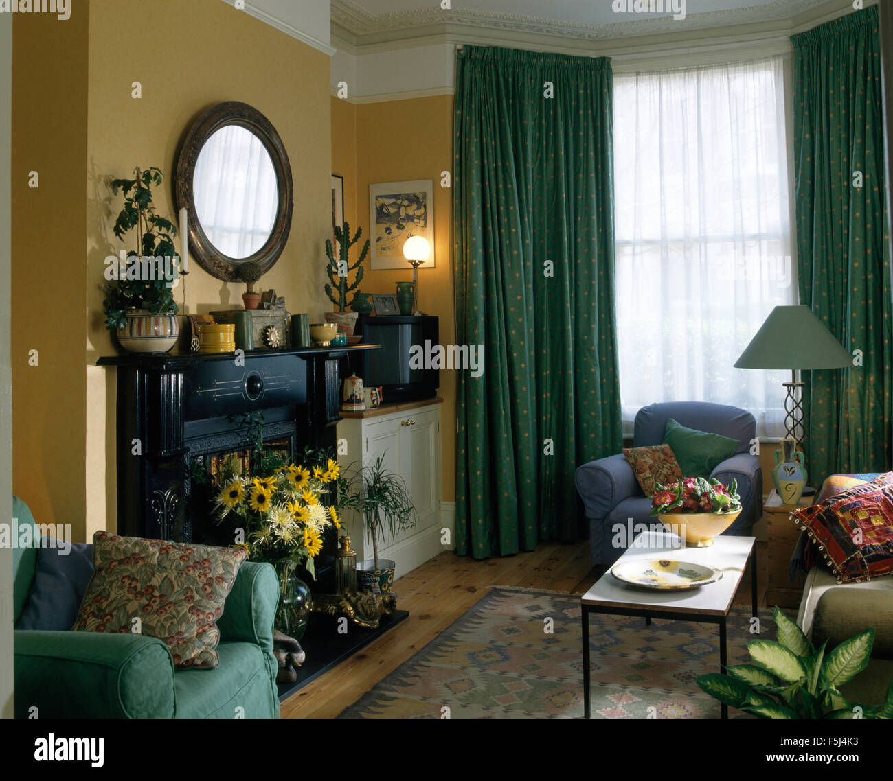 Vaso di giallo dei fiori estivi nel camino in novanta soggiorno con tende di colore verde Foto Stock