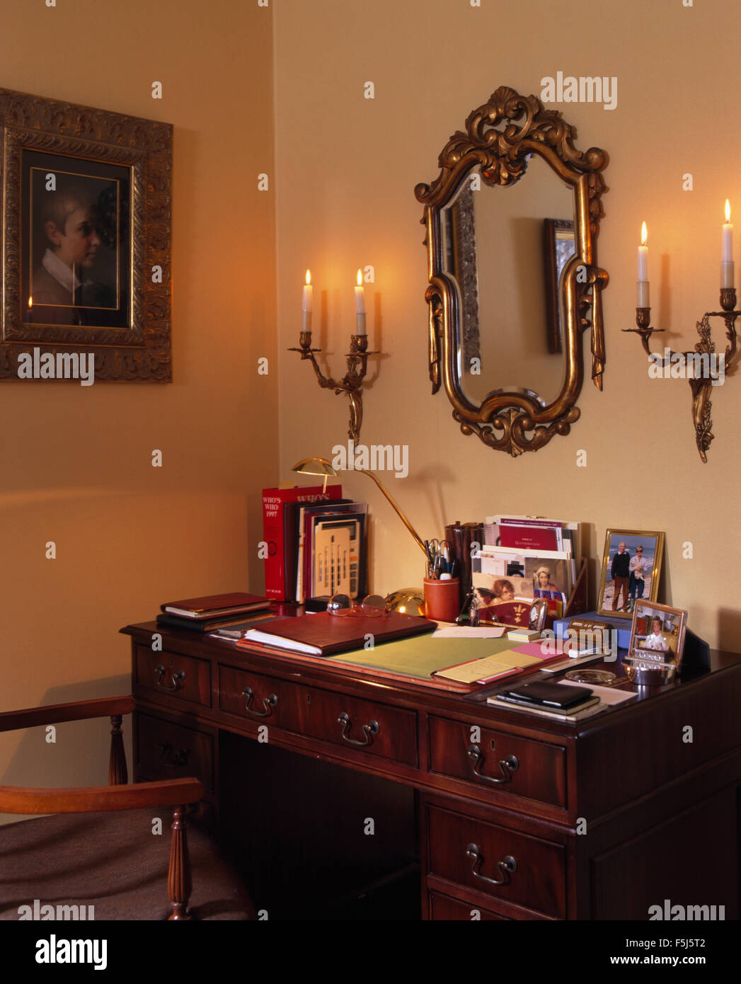 Le candele accese in appliques su entrambi i lati di un vintage specchio dorato sopra la scrivania in un studio degli anni novanta Foto Stock